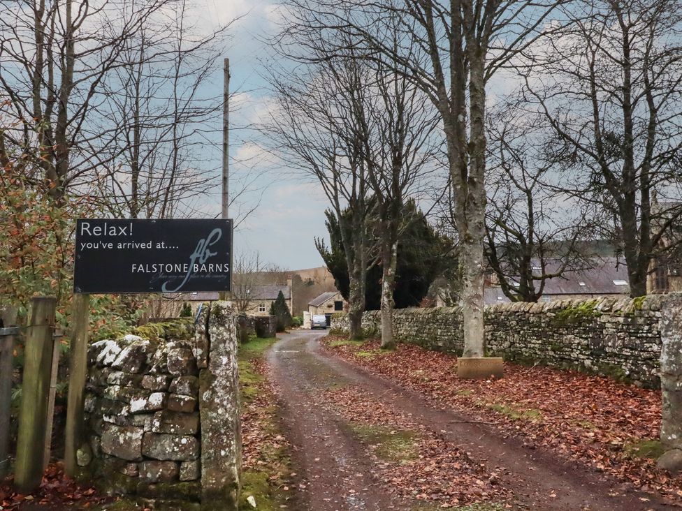 A sign at the entrance to Falstone Barns along a tree-lined road in Hexham