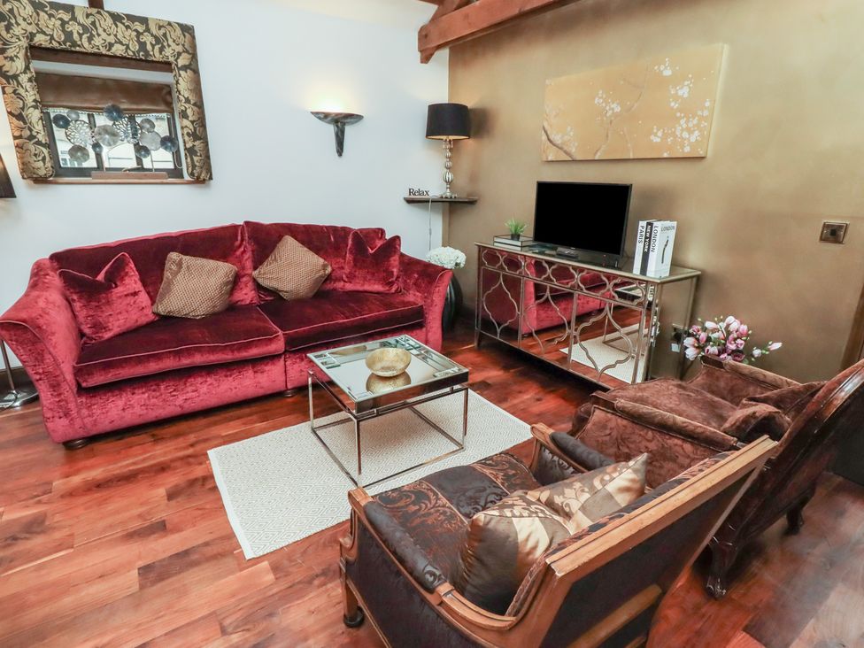 A living room with a red sofa and armchairs at The Opulent in Hexham