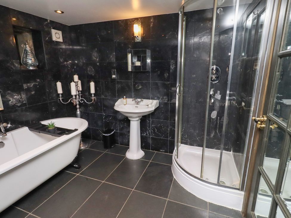 A bathroom with a bathtub, sink, shower, and candle holder at The Opulent in Hexham
