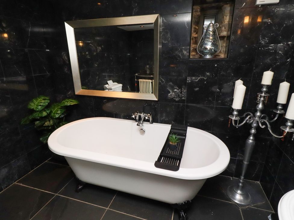 A bathroom featuring a bathtub, mirror, and candles at The Opulent in Hexham