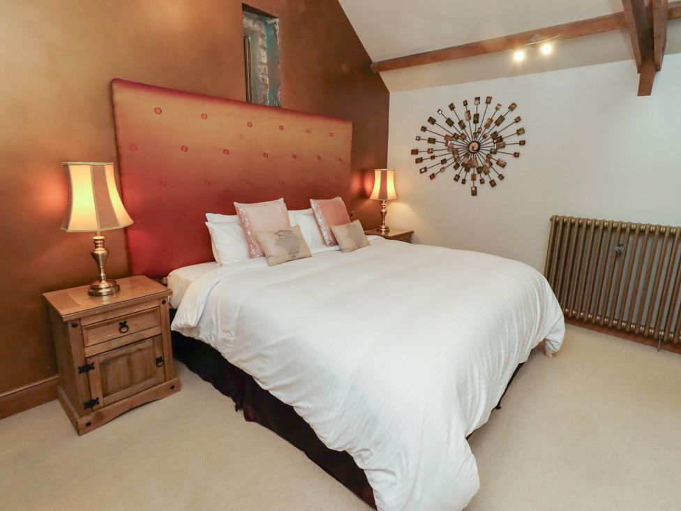 A bedroom with a bed, nightstand, lamp, and radiator at The Classic in Hexham