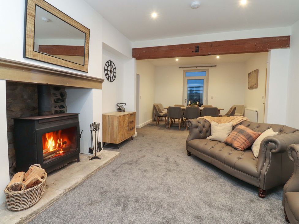 A living room with a fireplace and dining area at The Farm House in Skipton
