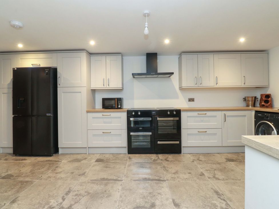 A kitchen with refrigerator, oven, microwave, and cabinets at The Farm House in Skipton