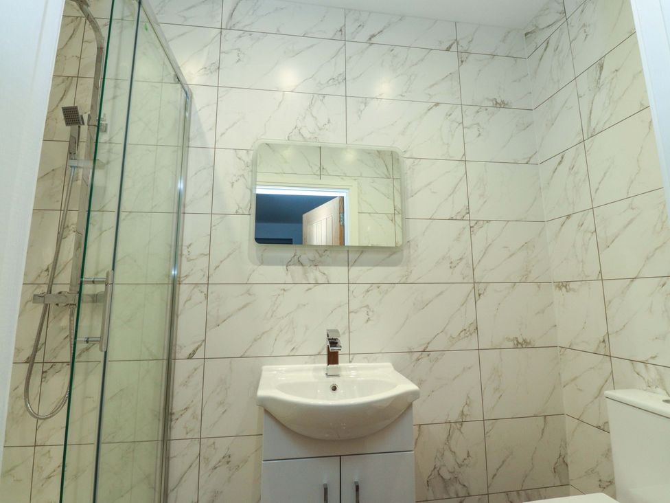 A bathroom with a shower, sink, and mirror at The Farm House in Skipton