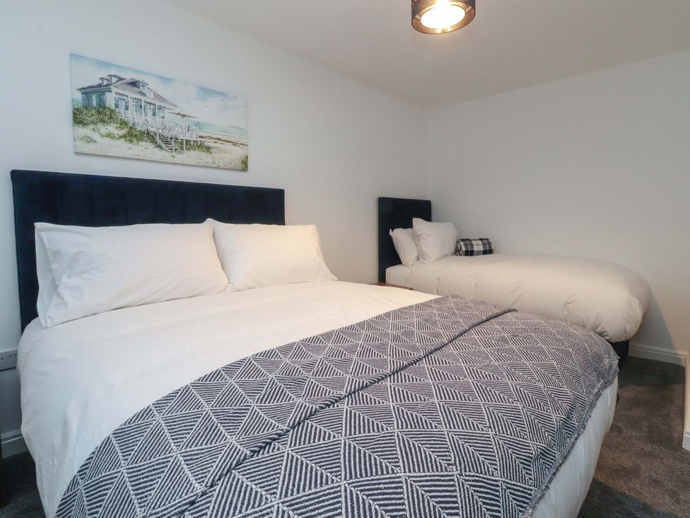 A bedroom with two beds and a painting on the wall at The Farm House in Skipton