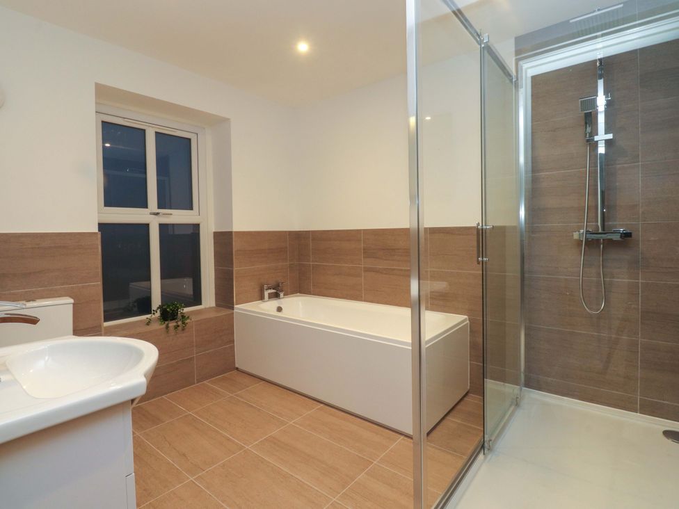 A bathroom with a shower, bath tub and sink at The Farm House in Skipton