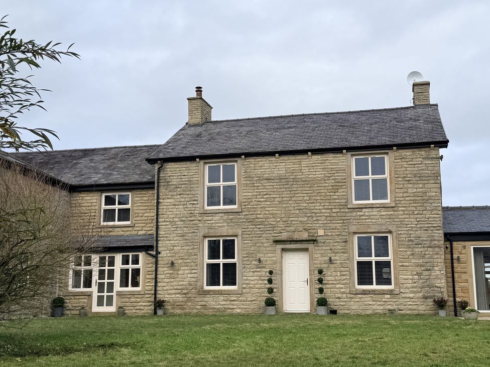 A stone house with windows and a door surrounded by grass at The Farm House in Wigglesworth near Settle