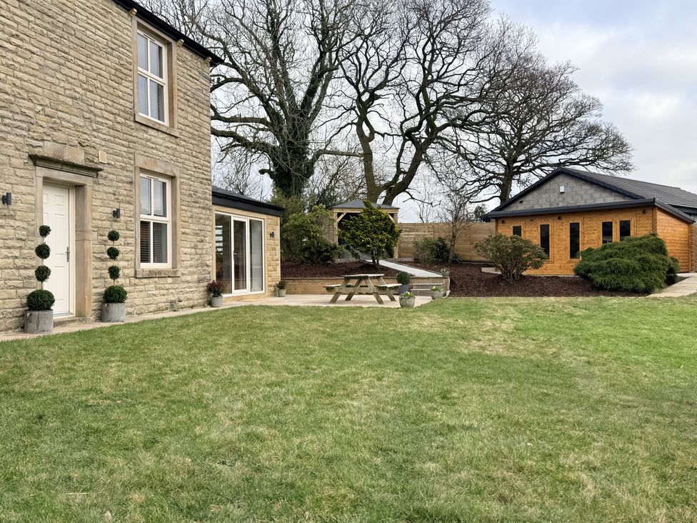 A garden with a stone house and wooden cabin at The Farm House in Wigglesworth near Settle