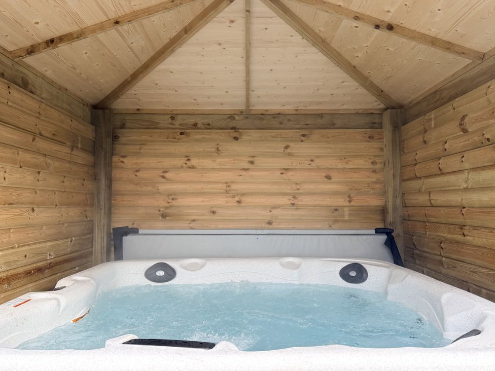 A hot tub inside a wooden structure at The Farm House in Wigglesworth near Settle