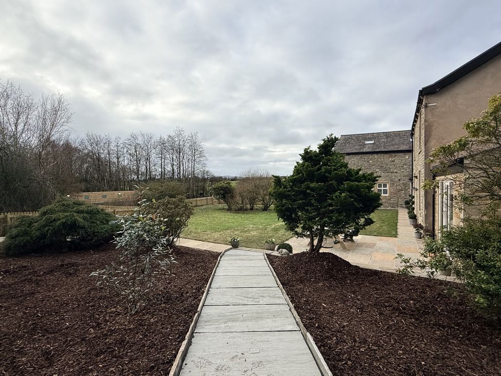 A garden with a pathway and bushes at The Farm House near Wigglesworth