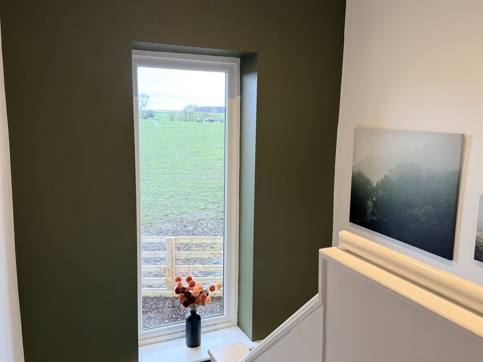 A staircase with a vase of flowers and pictures in the wall at The Farm House in Wigglesworth near Settle
