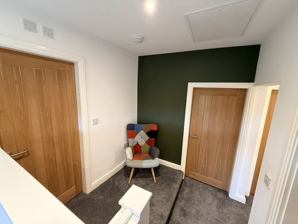 A hallway with an armchair and two doors at The Farm House in Wigglesworth near Settle