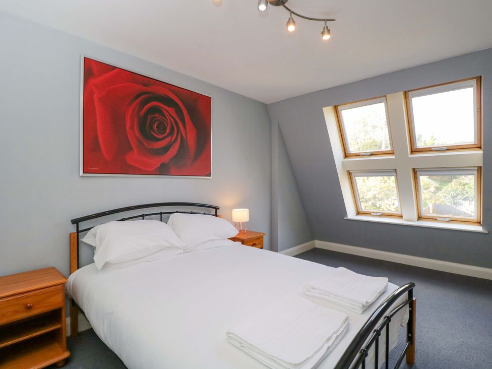 A bedroom with a bed and windows at Lady Of Lourdes in Whitchurch, Herefordshire