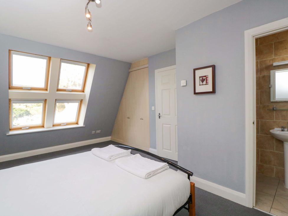A bedroom with a bed and windows at Lady Of Lourdes in Whitchurch, Herefordshire