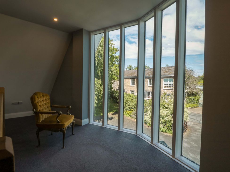 A sitting room with a chair and large windows at Lady Of Lourdes in Whitchurch, Herefordshire