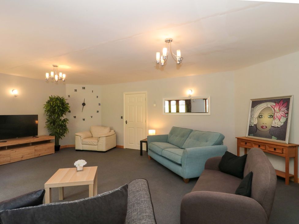 A living room with a sofa, television, and artwork at Lady Of Lourdes in Whitchurch, Herefordshire