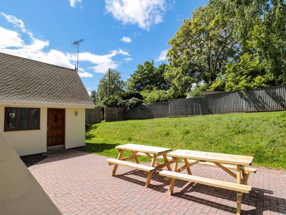 An outdoor area with picnic tables and a house at Lady Of Lourdes Whitchurch, Herefordshire