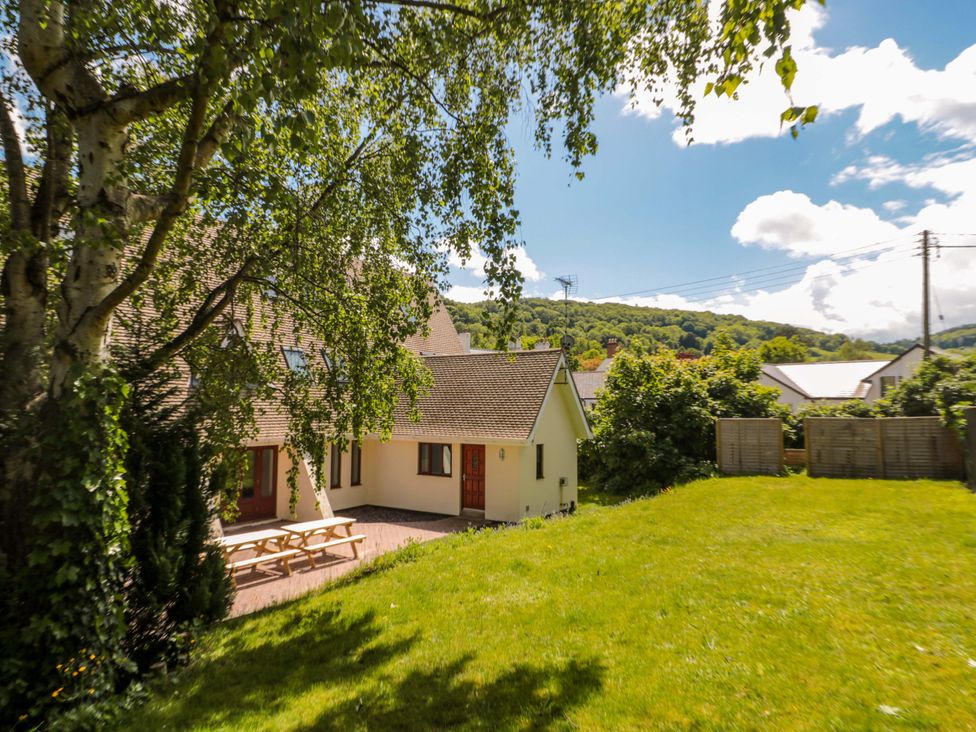 An outdoor view of a house with lawn and trees at Lady Of Lourdes in Whitchurch, Herefordshire