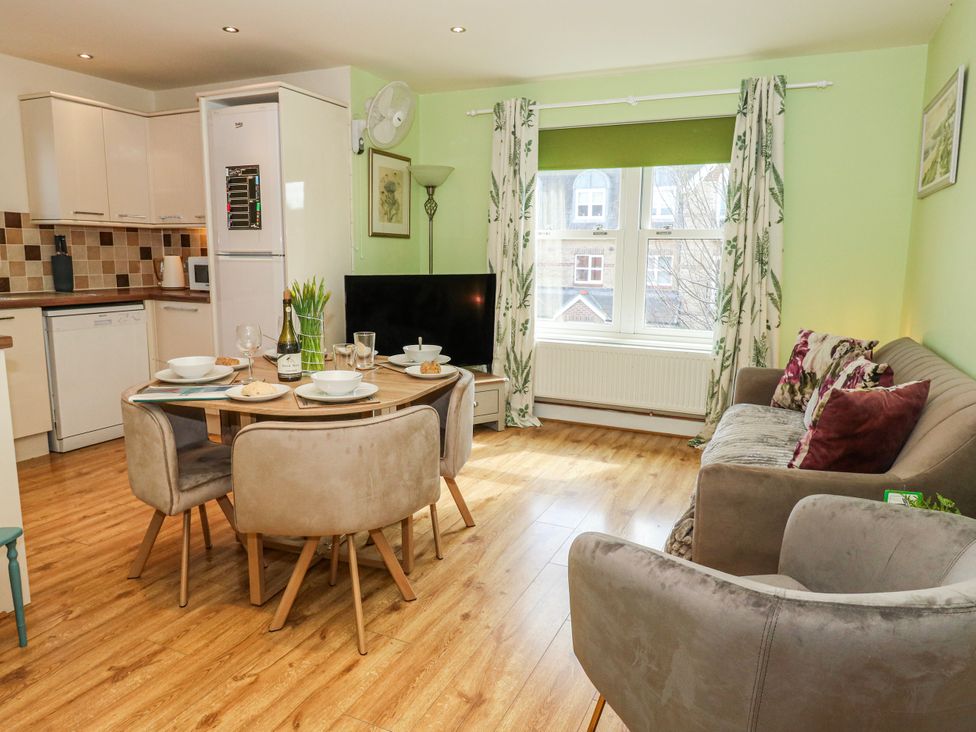 A living room with a dining table and kitchen appliances at Rodwell Holt in Weymouth
