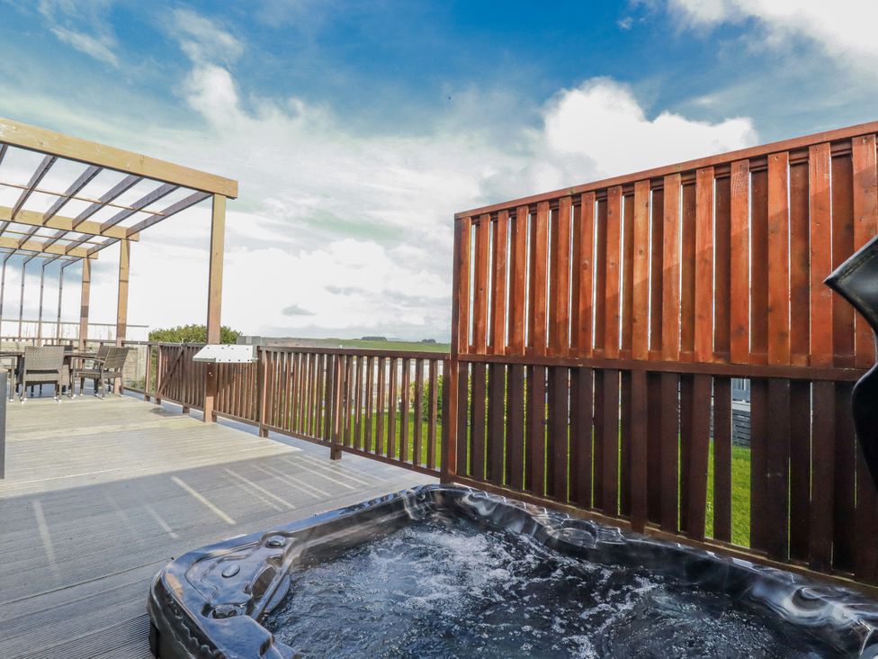 An outdoor deck with a hot tub and seating area at Adelaide in Redruth