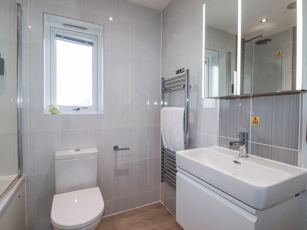 A bathroom with a toilet, wash basin, shower, and towel warmer at Adelaide in Redruth