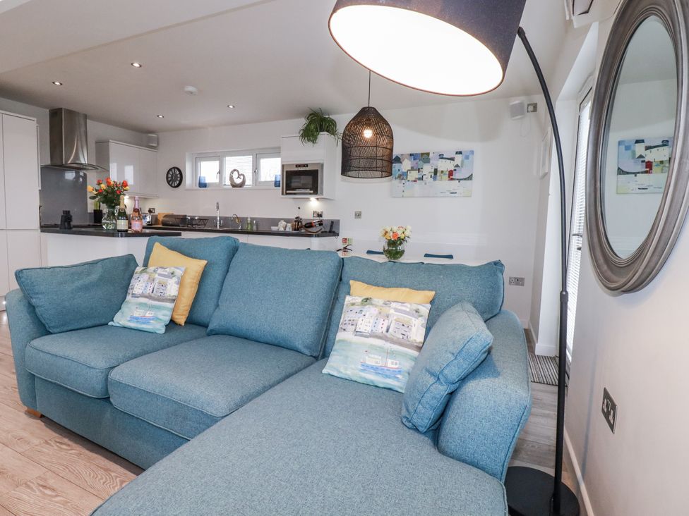 A living room with a sofa and kitchen in The Adelaide at Portreath
