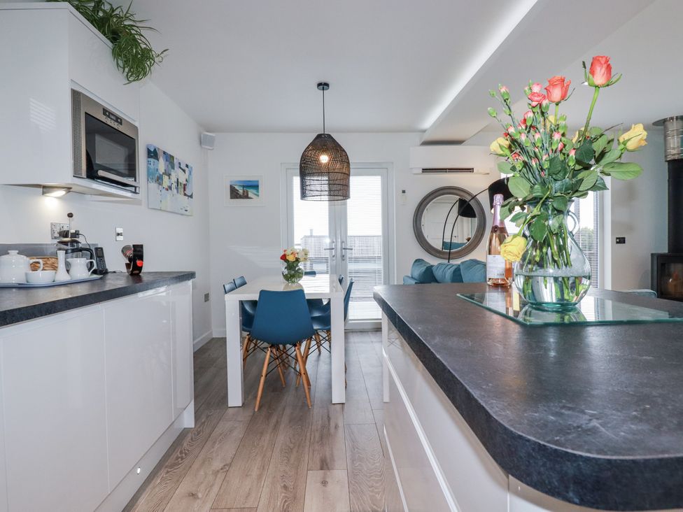 A kitchen with dining area and flower arrangement at Adelaide in Portreath