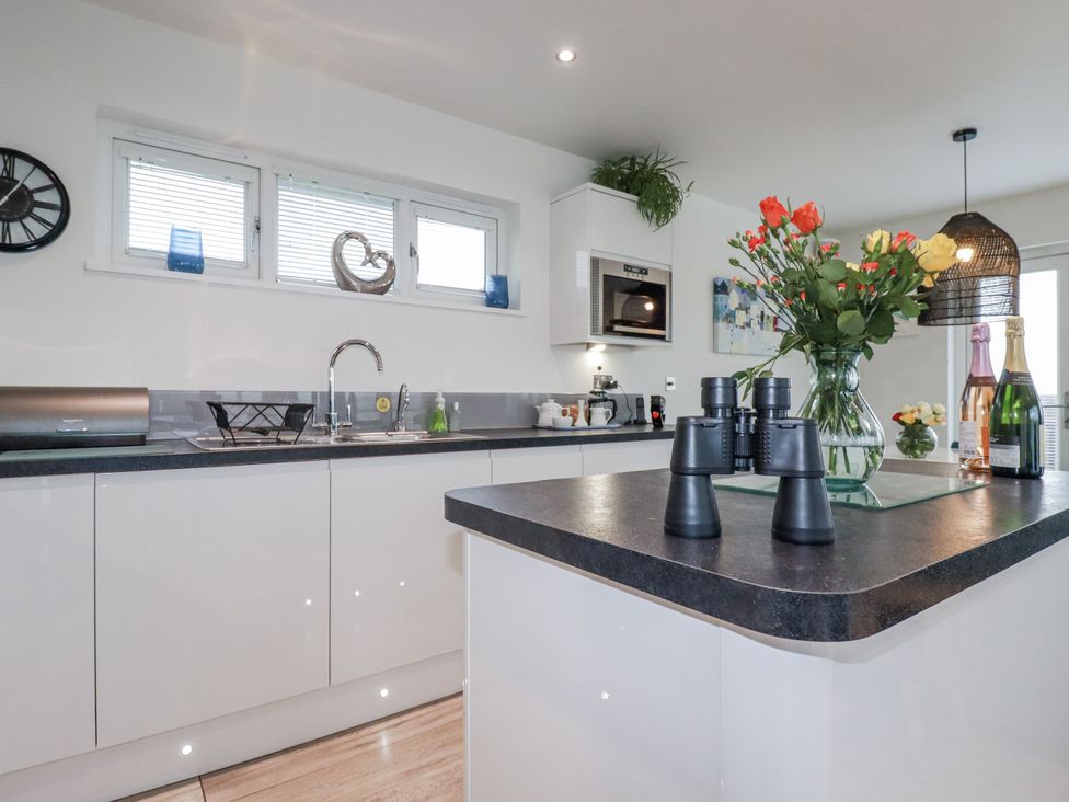 A kitchen with flowers and utensils at Adelaide in Portreath
