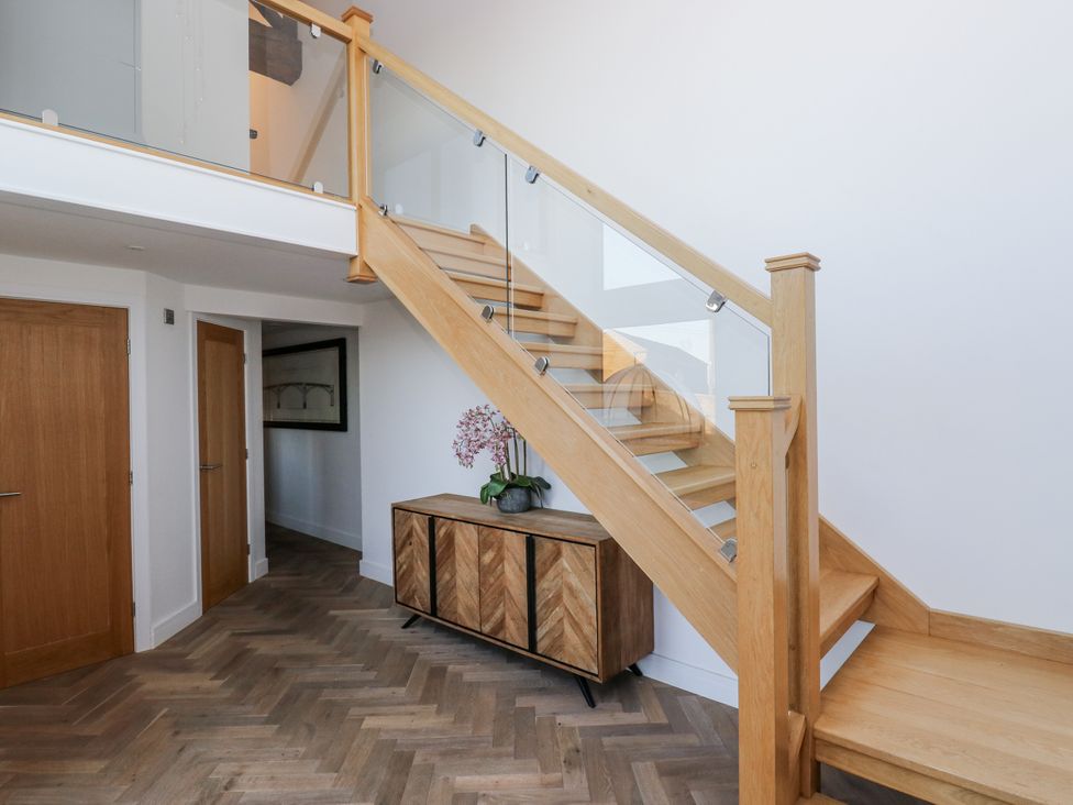 A hallway with a staircase and cabinet at The Robins Nest 