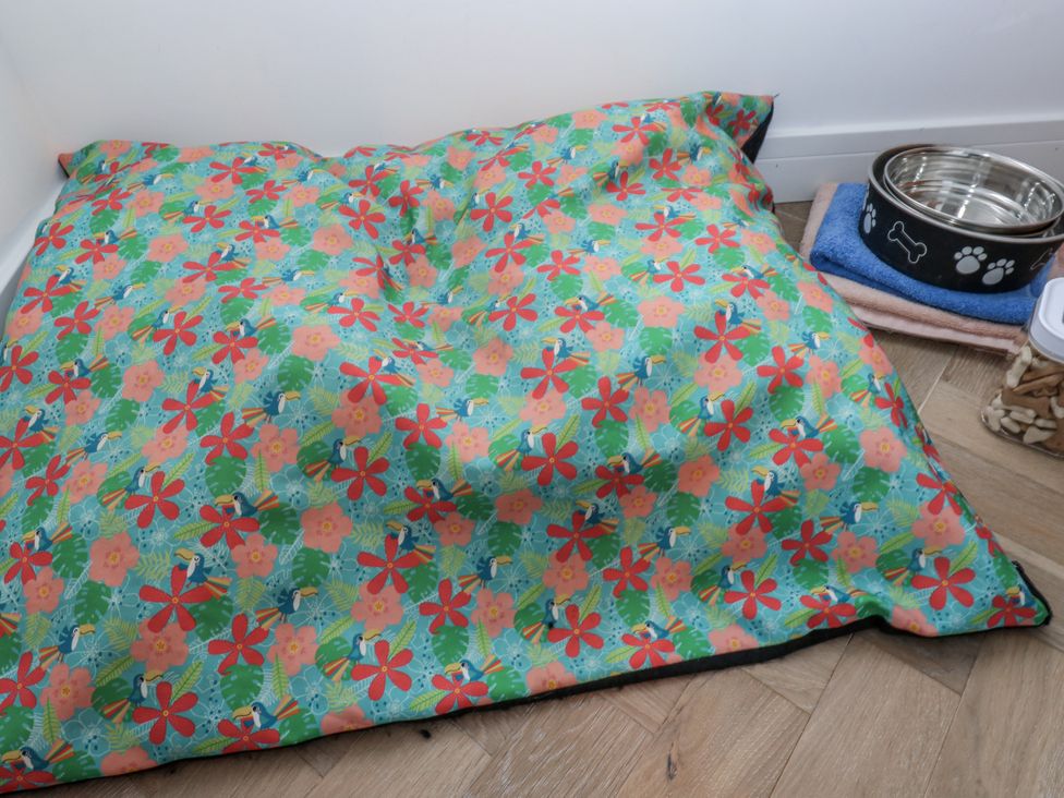 A pet bed and food bowl in an indoor pet area at The Robins Nest