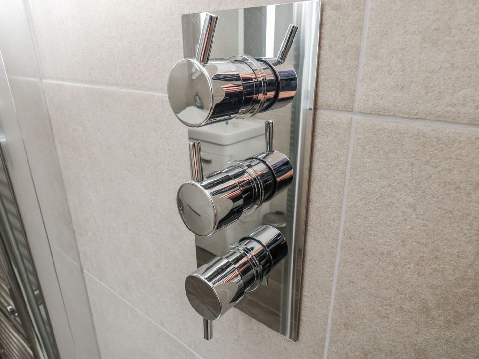A set of chrome shower controls mounted on a wall in a bathroom at The Robins Nest