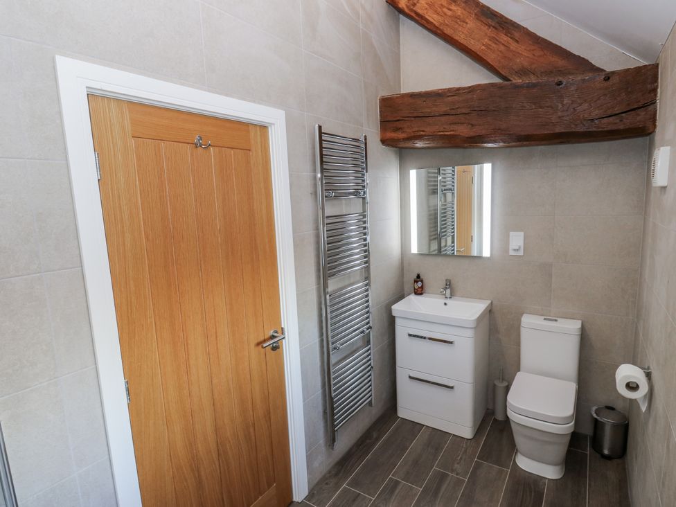 A bathroom with a sink, toilet, mirror, and towel radiator at The Robins Nest in 