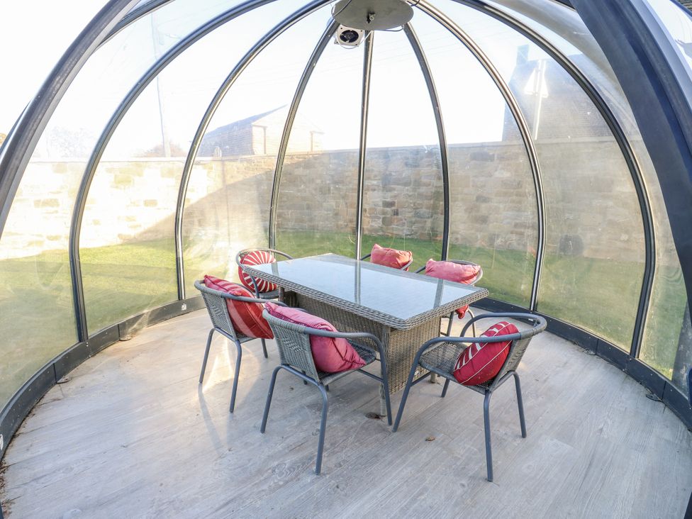 A conservatory with a glass dome table and chairs at The Robins Nest