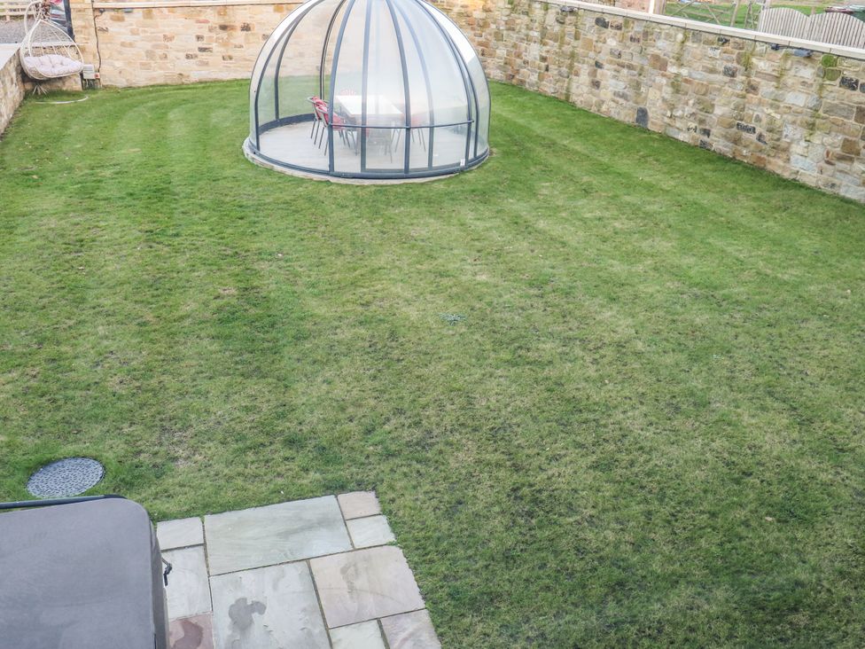 A garden with a glass structure and seating area at The Robins Nest