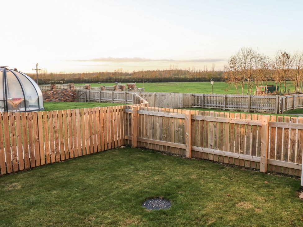 A garden with a lawn and wooden fence at The Robins Nest 