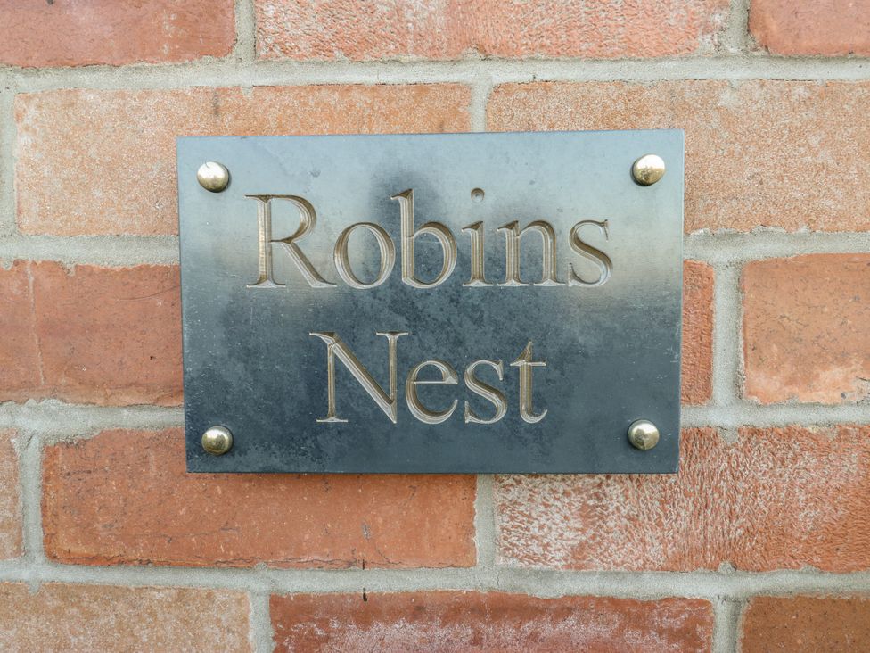 A nameplate installed on a brick wall at The Robins Nest 