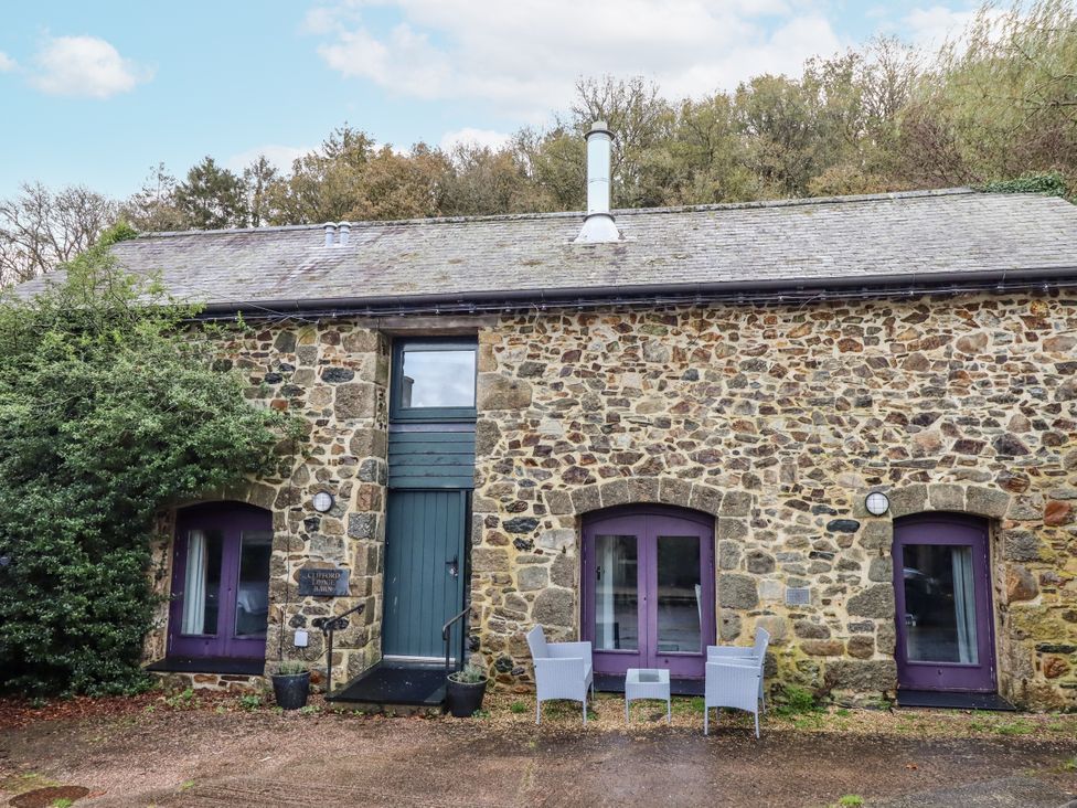 An outdoor view of a stone building with chairs at Clifford Lodge Barn