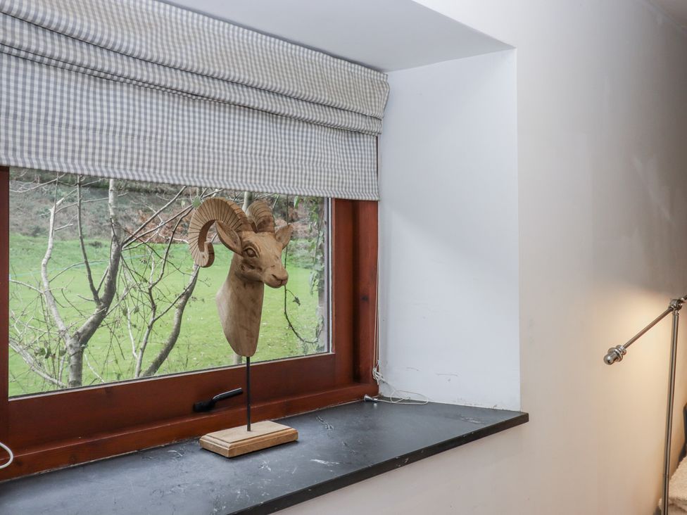 A wooden ram head sculpture on a windowsill in a sitting room at Clifford Lodge Barn