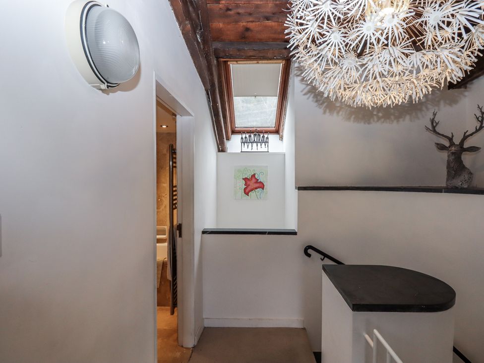 A hallway with a light fixture and painting at Clifford Lodge Barn