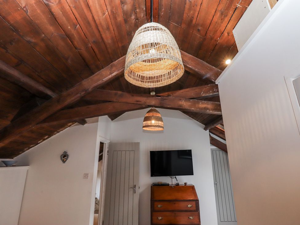 A bedroom with a wooden cabinet and TV at Clifford Lodge Barn 