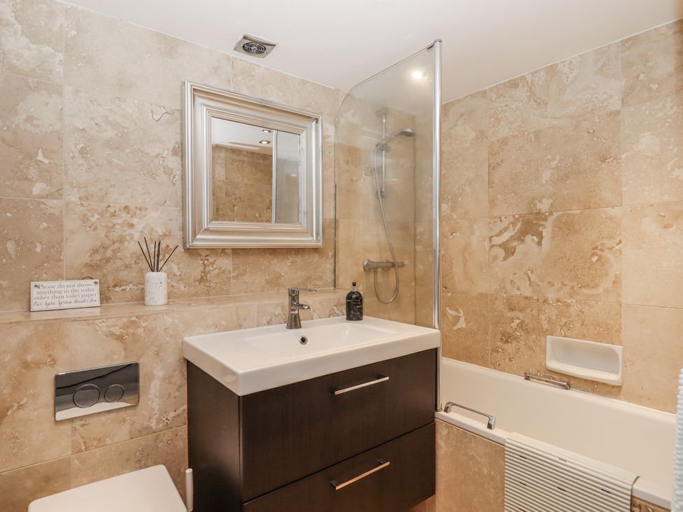 A bathroom featuring a sink, toilet, bathtub, and mirror at Clifford Lodge Barn