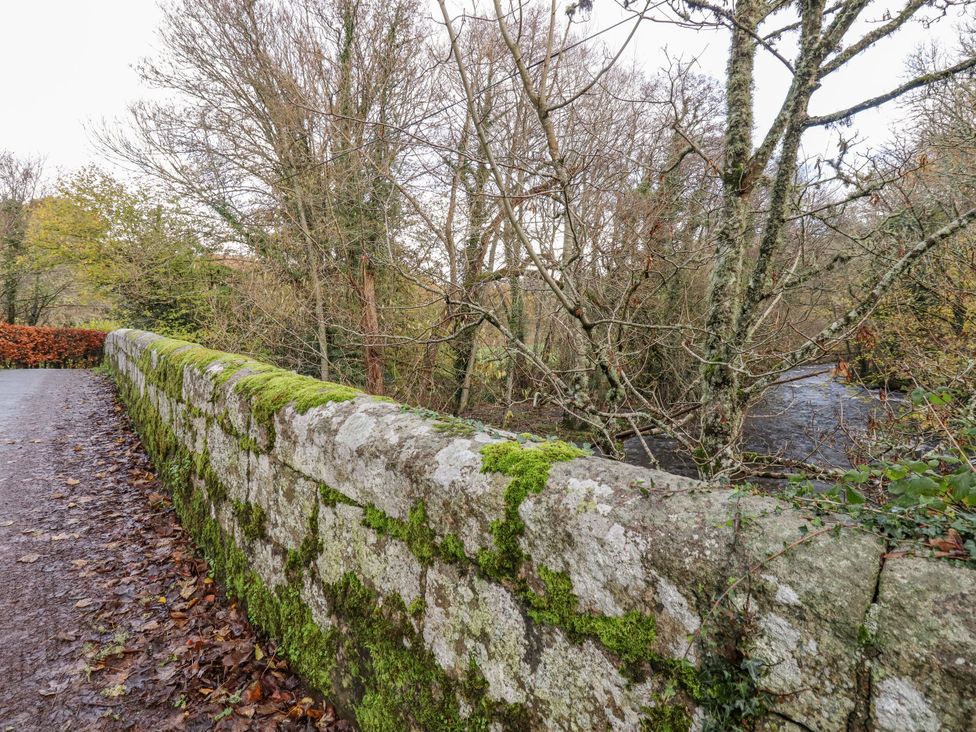 A stone wall covered in moss next to a stream at Clifford Lodge Barn
