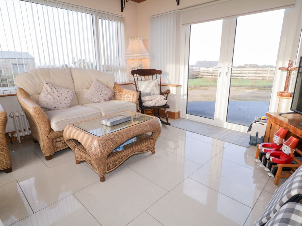 A conservatory with a sofa and coffee table at Storey and Half House in Annagry
