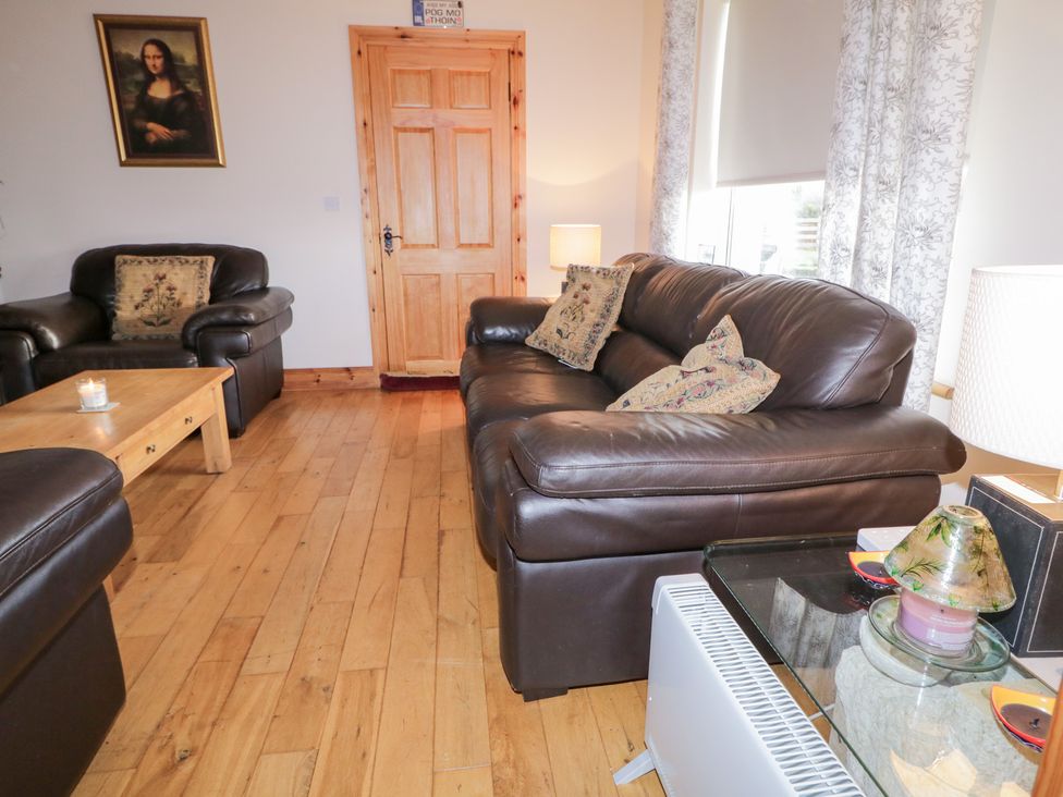 A living room with sofas, a table, and a door at Storey and Half House in Annagry