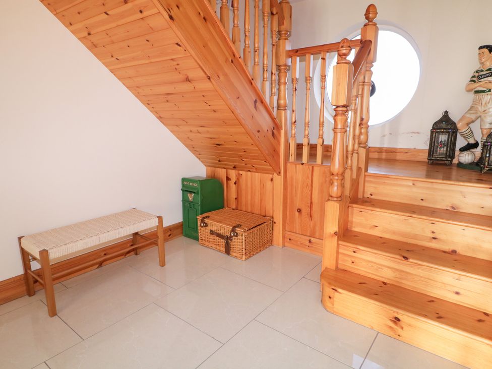 A hallway with a staircase and storage box at Storey and Half House, Annagry
