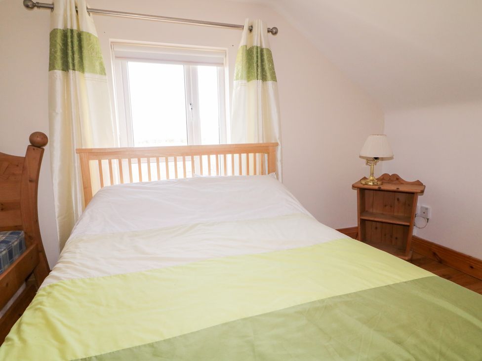 A bedroom with a bed and bedside table at Storey and Half House Annagry