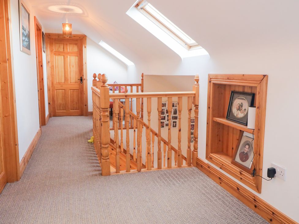 A hallway with a stair railing and pictures at Storey and Half House Annagry
