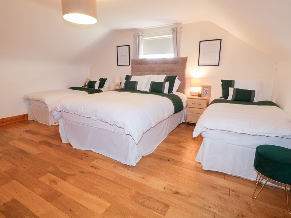 A bedroom with three beds and a nightstand at Storey and Half House Annagry