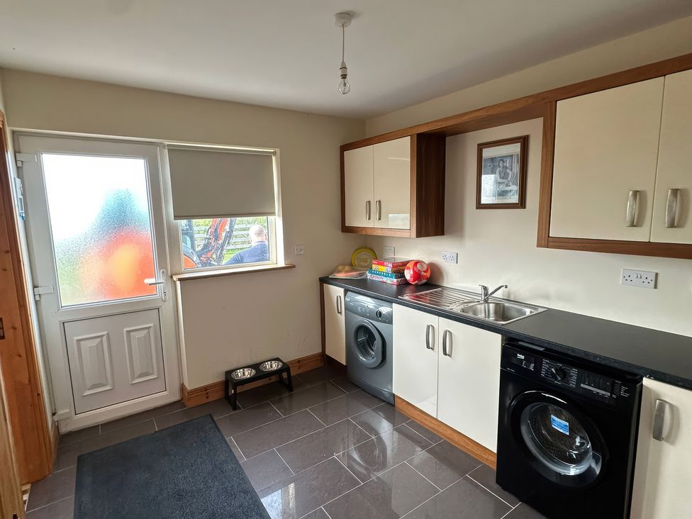 A utility room with a washing machine and sink at Storey and Half House Near Annagry, County Donegal