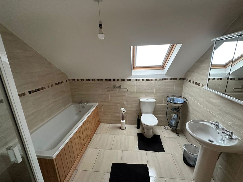 A bathroom with bathtub, toilet, and sink at Storey and Half House Near Annagry, County Donegal